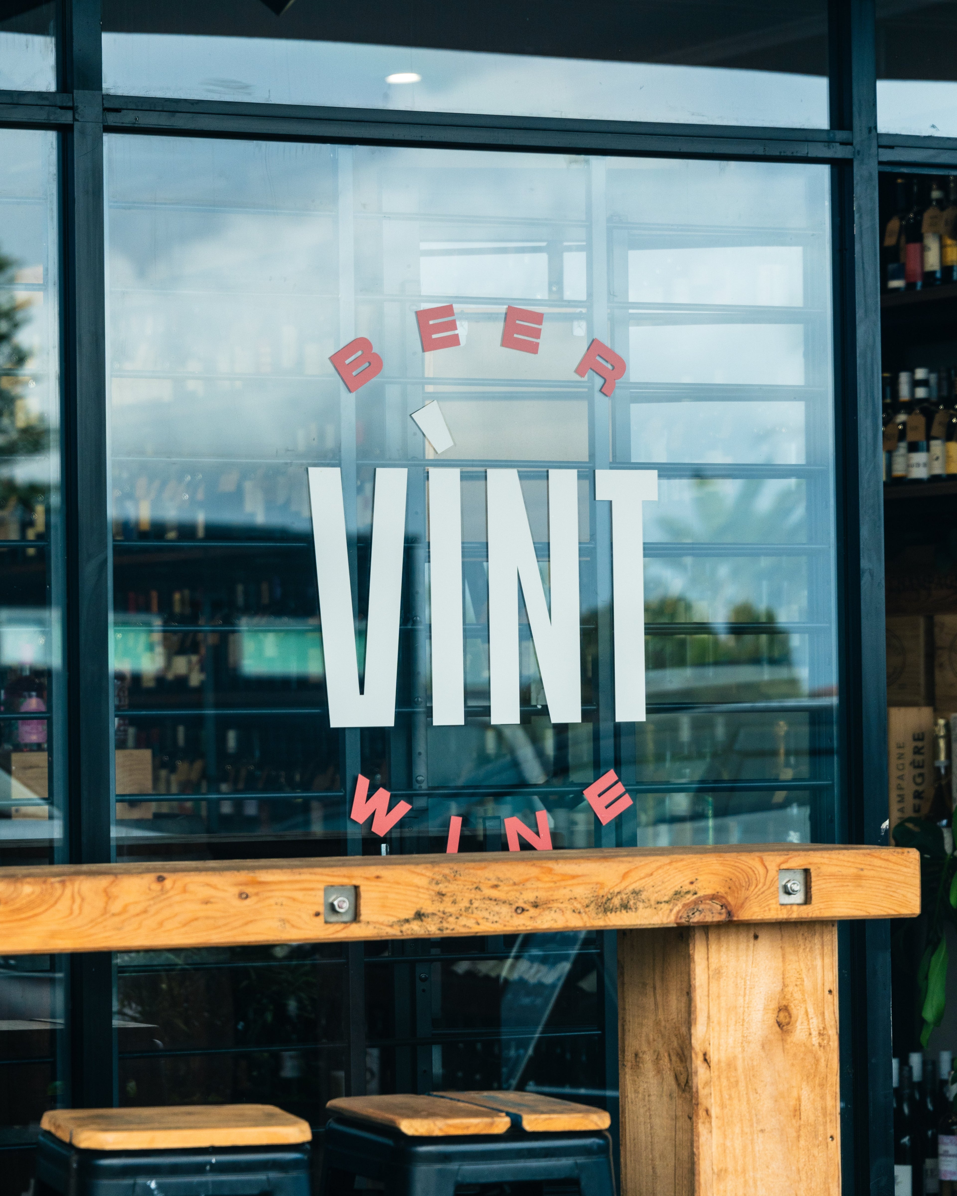 Glass door with 'BEER VINT WINE' text and wooden bench in front